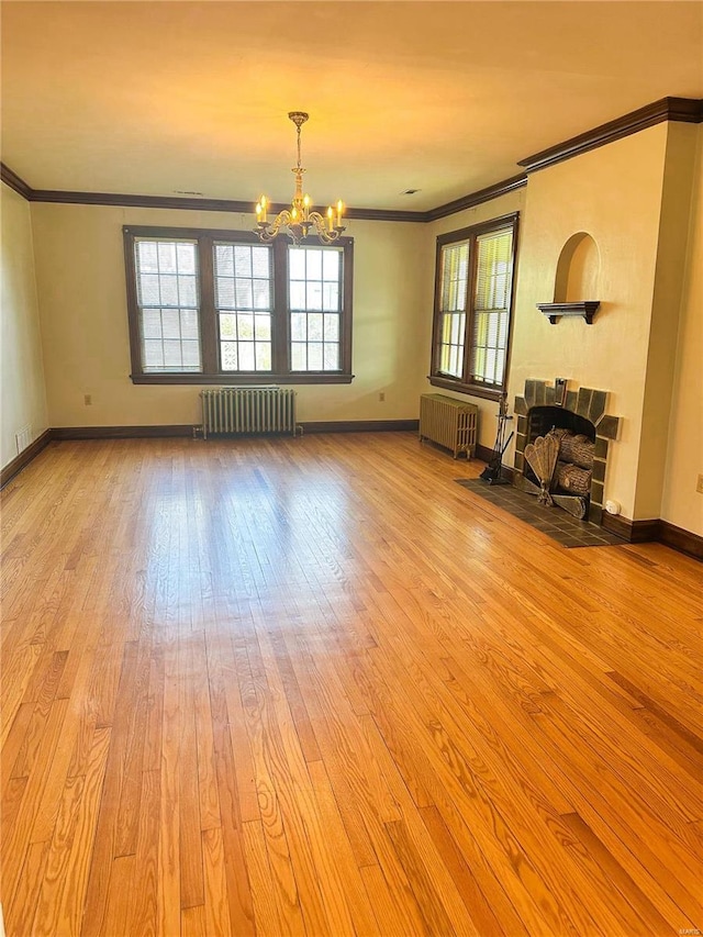 unfurnished living room with ornamental molding, radiator, a stone fireplace, and hardwood / wood-style flooring