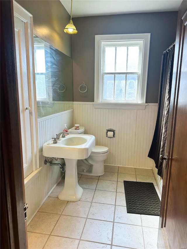 full bathroom with a wainscoted wall, toilet, and tile patterned floors