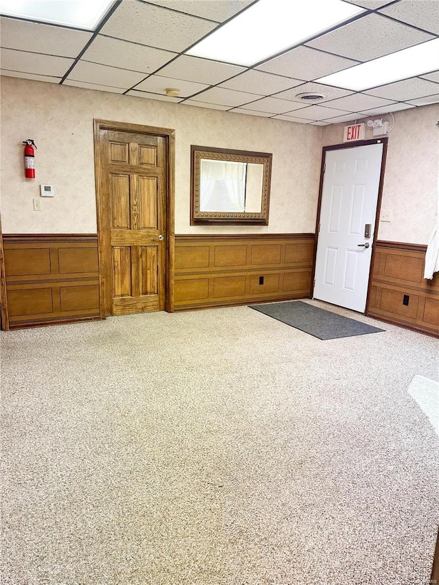 unfurnished room with wainscoting, carpet, and a paneled ceiling