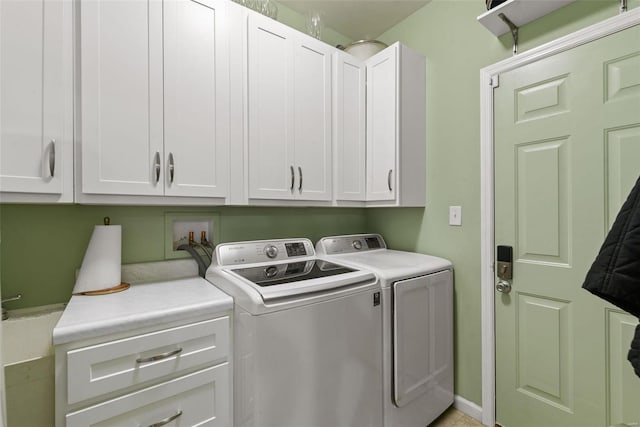 clothes washing area featuring cabinets and separate washer and dryer