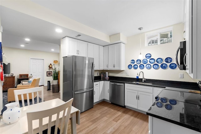 kitchen featuring appliances with stainless steel finishes, sink, white cabinetry, and hanging light fixtures