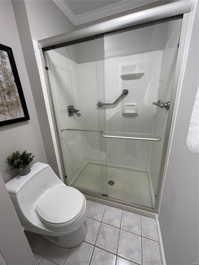 bathroom featuring ornamental molding, toilet, a shower with shower door, and tile patterned flooring