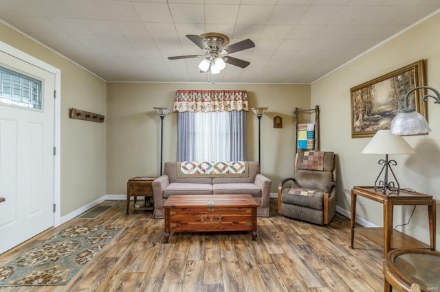 living room with crown molding, wood-type flooring, and ceiling fan