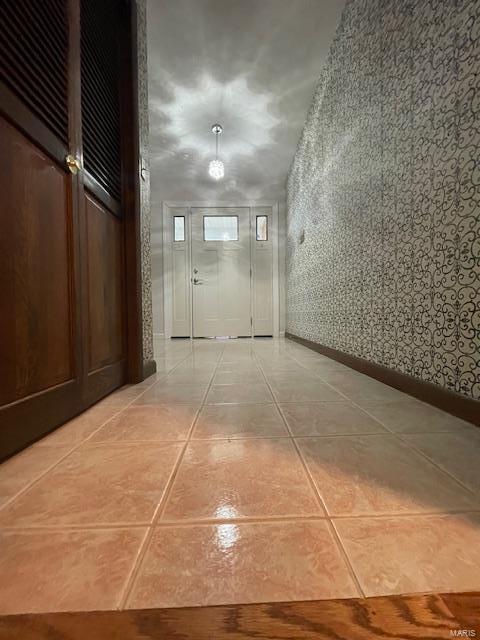 hall featuring wallpapered walls, baseboards, and light tile patterned floors