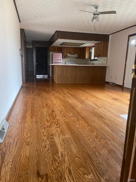 unfurnished living room featuring a ceiling fan, baseboards, visible vents, and wood finished floors