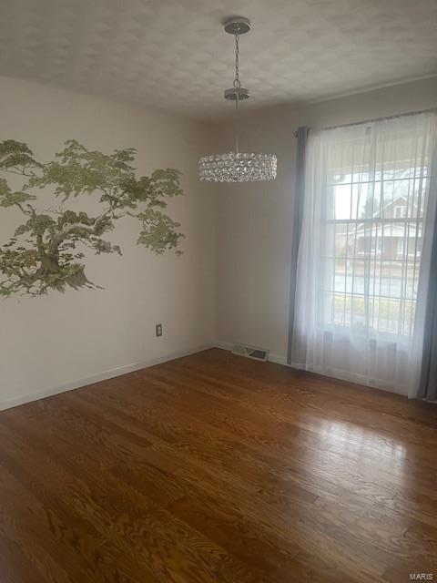 spare room featuring baseboards, visible vents, and wood finished floors