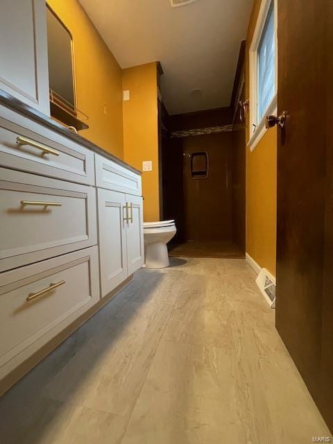 bathroom with a stall shower, visible vents, vanity, and toilet