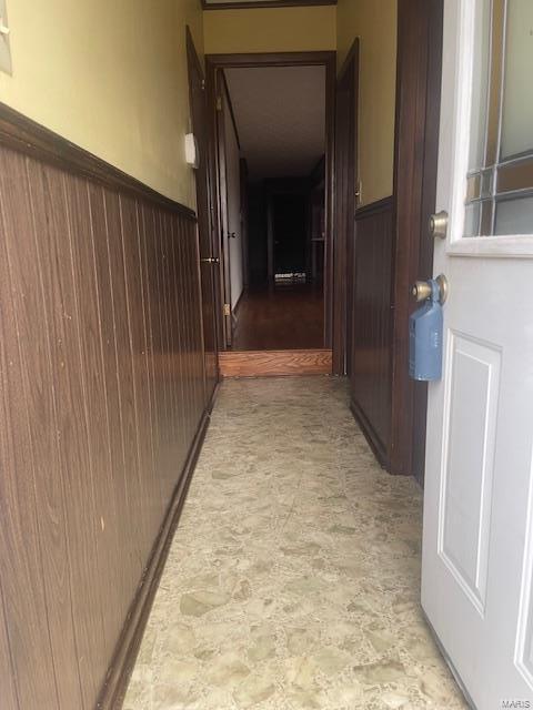 corridor featuring wainscoting and wooden walls