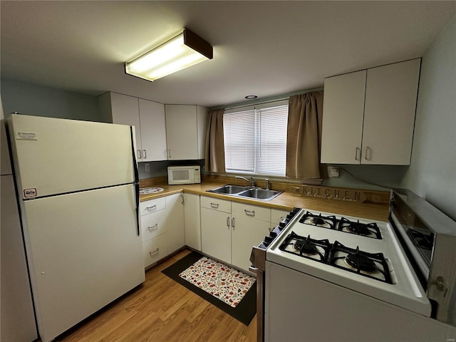 kitchen with white cabinetry, sink, white appliances, and light wood-type flooring