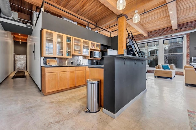 kitchen with a sink, stainless steel microwave, dark countertops, open floor plan, and concrete floors