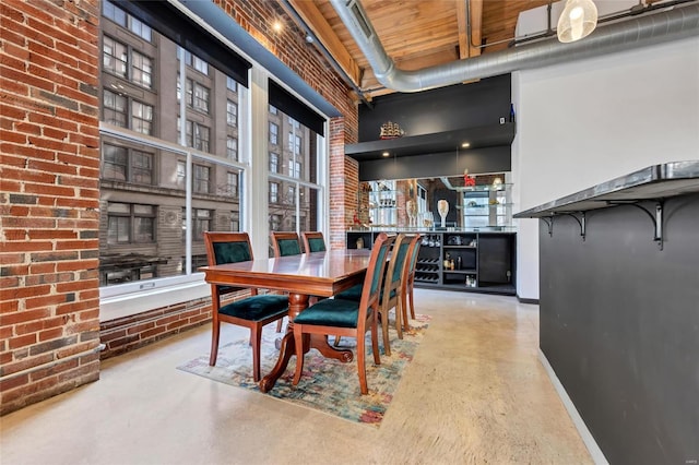 dining space with a high ceiling, concrete floors, and brick wall