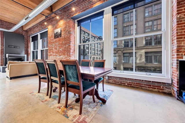 dining area featuring a high ceiling, concrete flooring, and brick wall