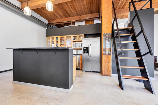 kitchen featuring white microwave, dark countertops, glass insert cabinets, concrete floors, and stainless steel refrigerator with ice dispenser