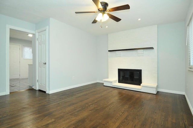 unfurnished living room with dark hardwood / wood-style flooring, ceiling fan, and a fireplace