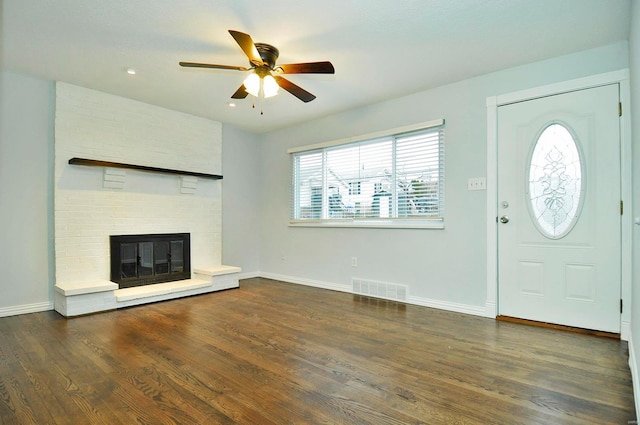 entryway featuring ceiling fan, a fireplace, and dark hardwood / wood-style floors