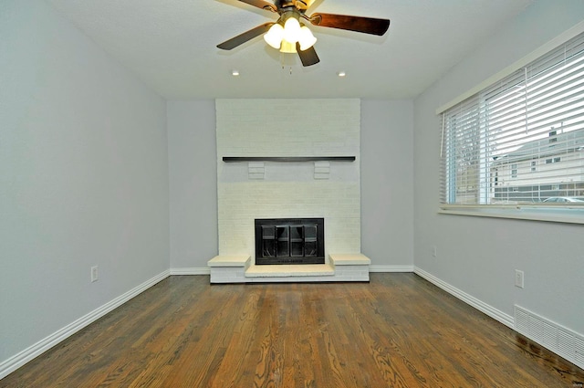 unfurnished living room with dark wood-type flooring, ceiling fan, and a fireplace