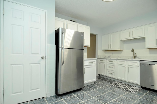 kitchen with stainless steel appliances, white cabinetry, sink, and a textured ceiling