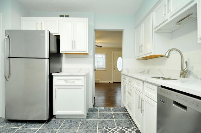 kitchen featuring stainless steel appliances, sink, decorative backsplash, and white cabinets