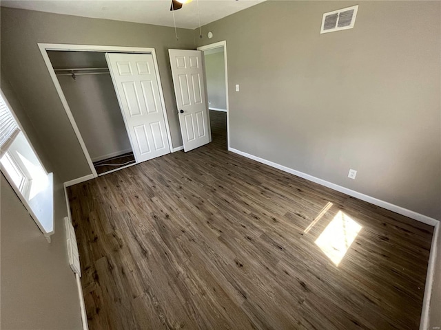 unfurnished bedroom featuring ceiling fan, dark hardwood / wood-style flooring, and a closet