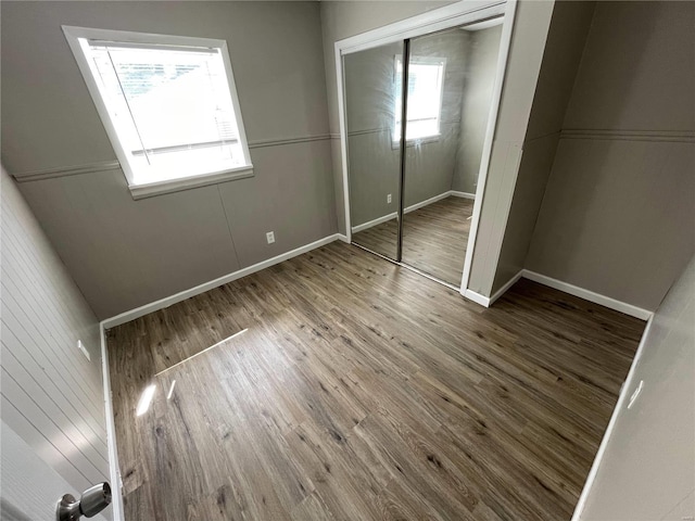 unfurnished bedroom featuring multiple windows, wood-type flooring, and a closet