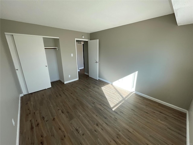 unfurnished bedroom with dark hardwood / wood-style floors and a closet