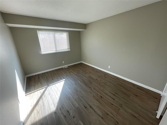 spare room with dark wood-type flooring and a textured ceiling