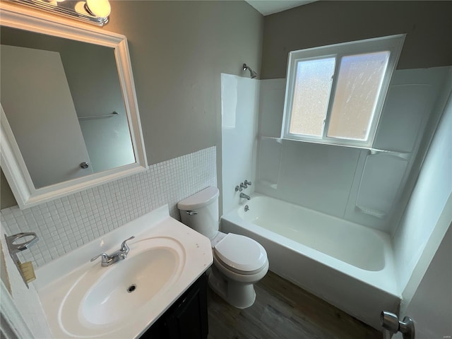 full bathroom featuring toilet,  shower combination, tile walls, vanity, and hardwood / wood-style floors