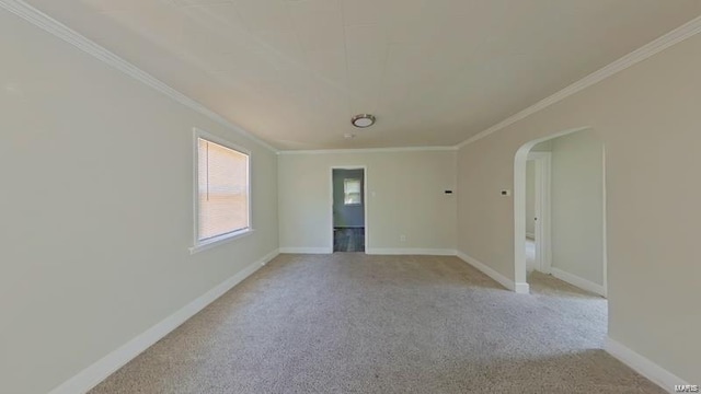 empty room with ornamental molding, arched walkways, light colored carpet, and baseboards