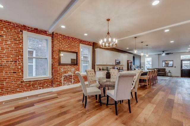 dining room with brick wall, beam ceiling, and light hardwood / wood-style flooring