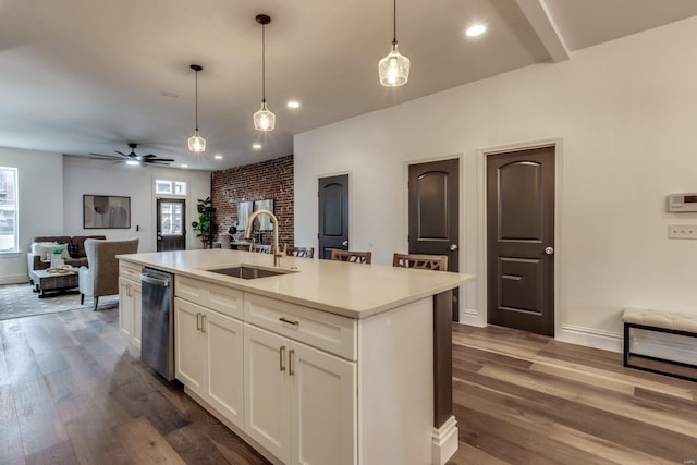 kitchen featuring sink, dark wood-type flooring, hanging light fixtures, white cabinets, and a center island with sink