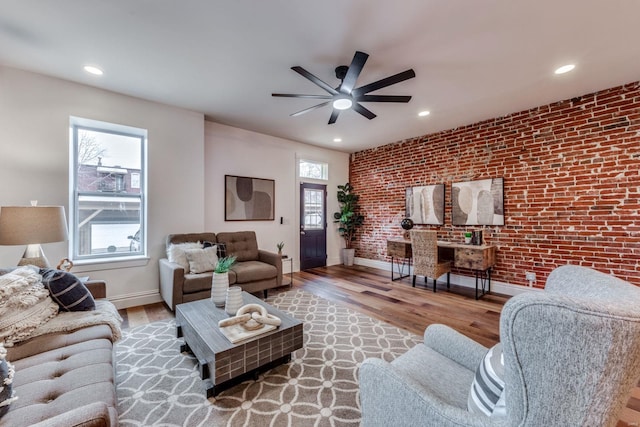 living room with hardwood / wood-style flooring, brick wall, and ceiling fan