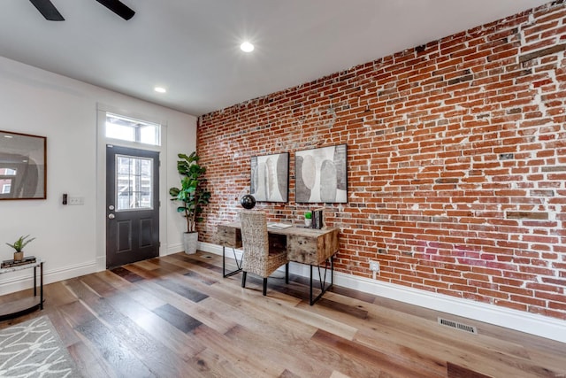 foyer featuring brick wall and light wood-type flooring