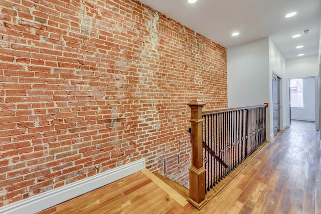 corridor featuring brick wall, a baseboard heating unit, and hardwood / wood-style floors