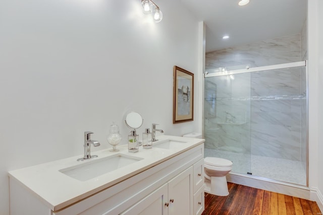 bathroom with wood-type flooring, toilet, a shower with door, and vanity