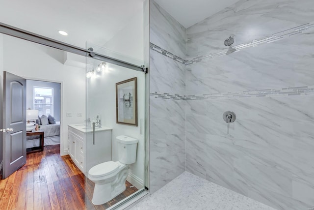 bathroom featuring hardwood / wood-style flooring, vanity, toilet, and a tile shower