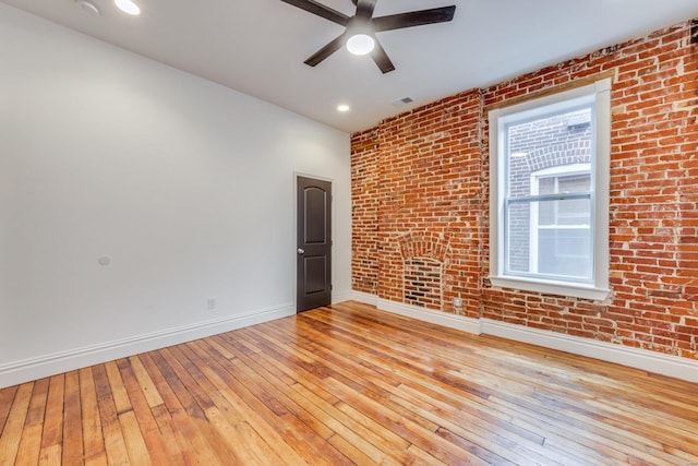 unfurnished room featuring brick wall, ceiling fan, and light hardwood / wood-style flooring