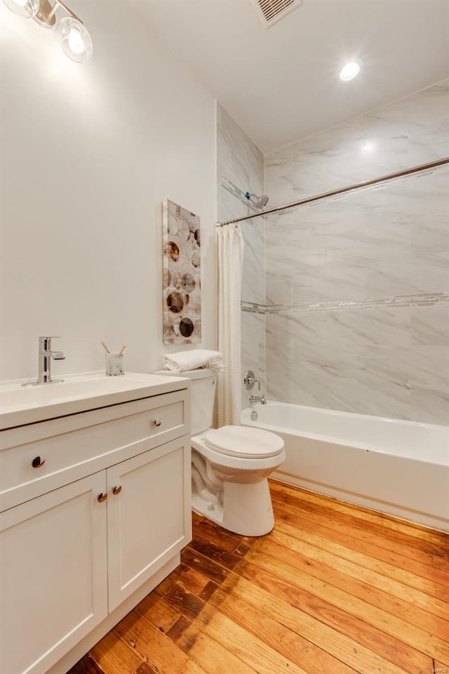 full bathroom featuring vanity, hardwood / wood-style floors, shower / bathtub combination with curtain, and toilet