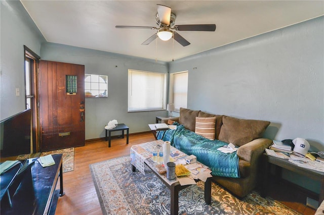 living area featuring ceiling fan, baseboards, and wood finished floors