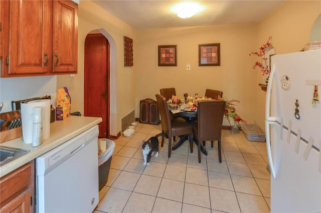 dining space with light tile patterned floors, visible vents, arched walkways, and baseboards