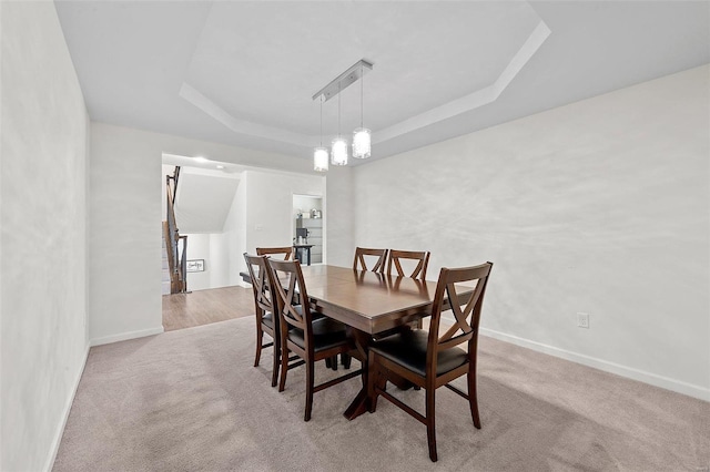 dining area featuring light colored carpet and a tray ceiling