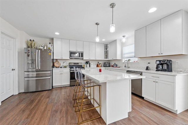 kitchen with white cabinetry, stainless steel appliances, a kitchen island, and pendant lighting