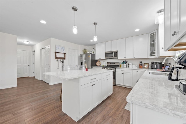 kitchen featuring appliances with stainless steel finishes, pendant lighting, sink, white cabinets, and a center island