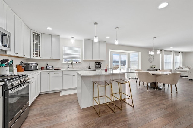 kitchen with stainless steel appliances, white cabinetry, a kitchen island, and sink