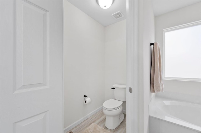 bathroom featuring hardwood / wood-style floors, toilet, and a bathing tub