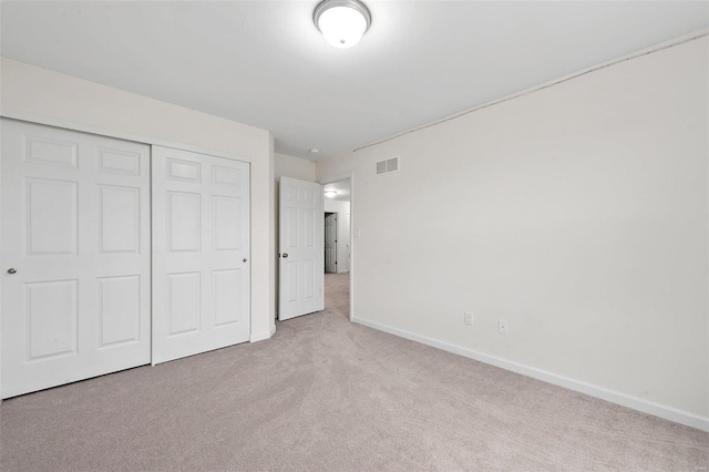 unfurnished bedroom with light colored carpet and a closet