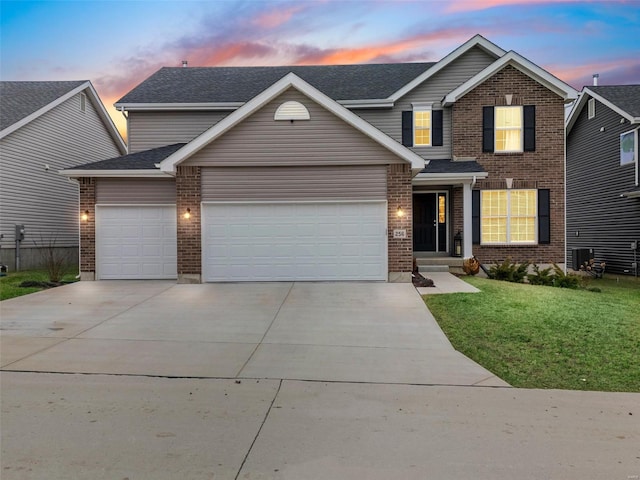 traditional-style house with an attached garage, brick siding, driveway, and a front yard