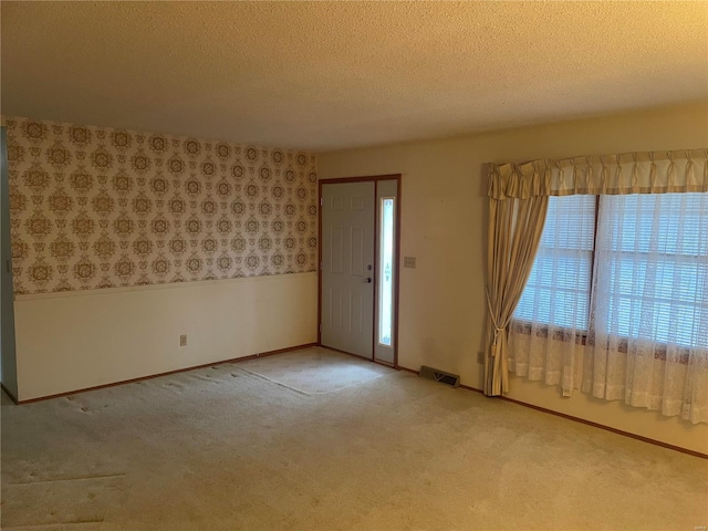 carpeted foyer with a textured ceiling