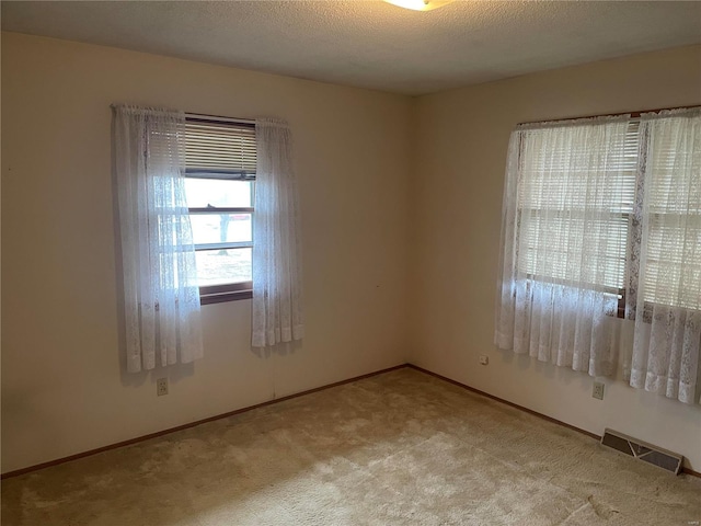 carpeted empty room with a textured ceiling