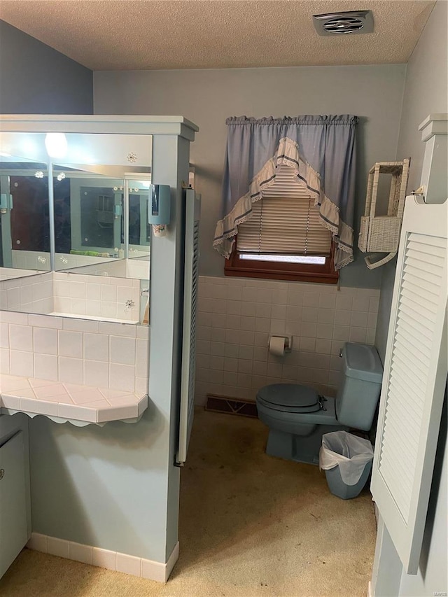 bathroom with tile walls, a textured ceiling, and toilet