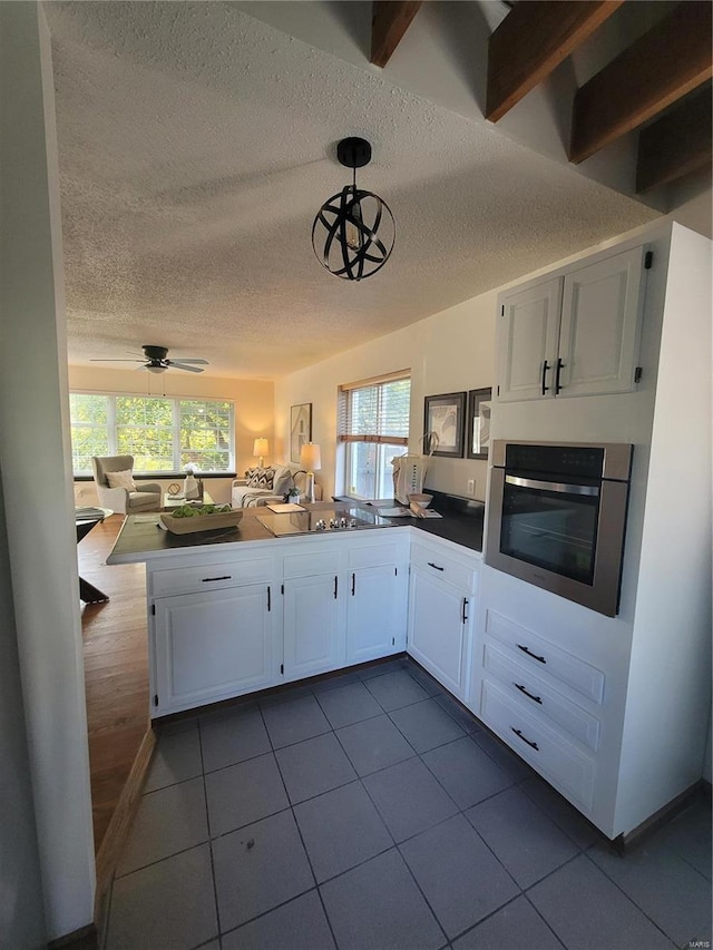 kitchen with stainless steel oven, decorative light fixtures, kitchen peninsula, ceiling fan, and white cabinets